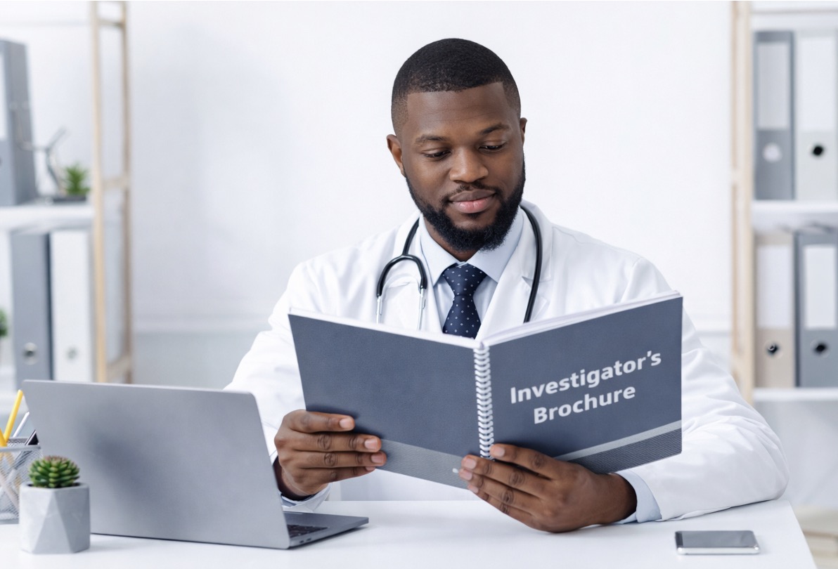 Doctor in white coat reading an Investigator's Brochure at desk with laptop in modern office setting.